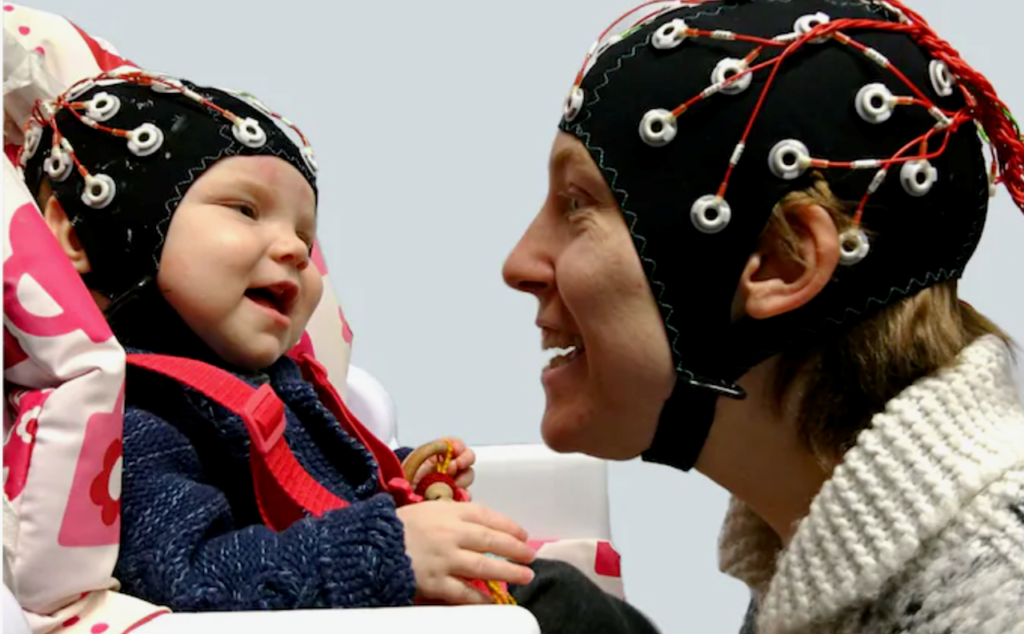 A parent and infant engaging in attunement play while wearing EEG caps
